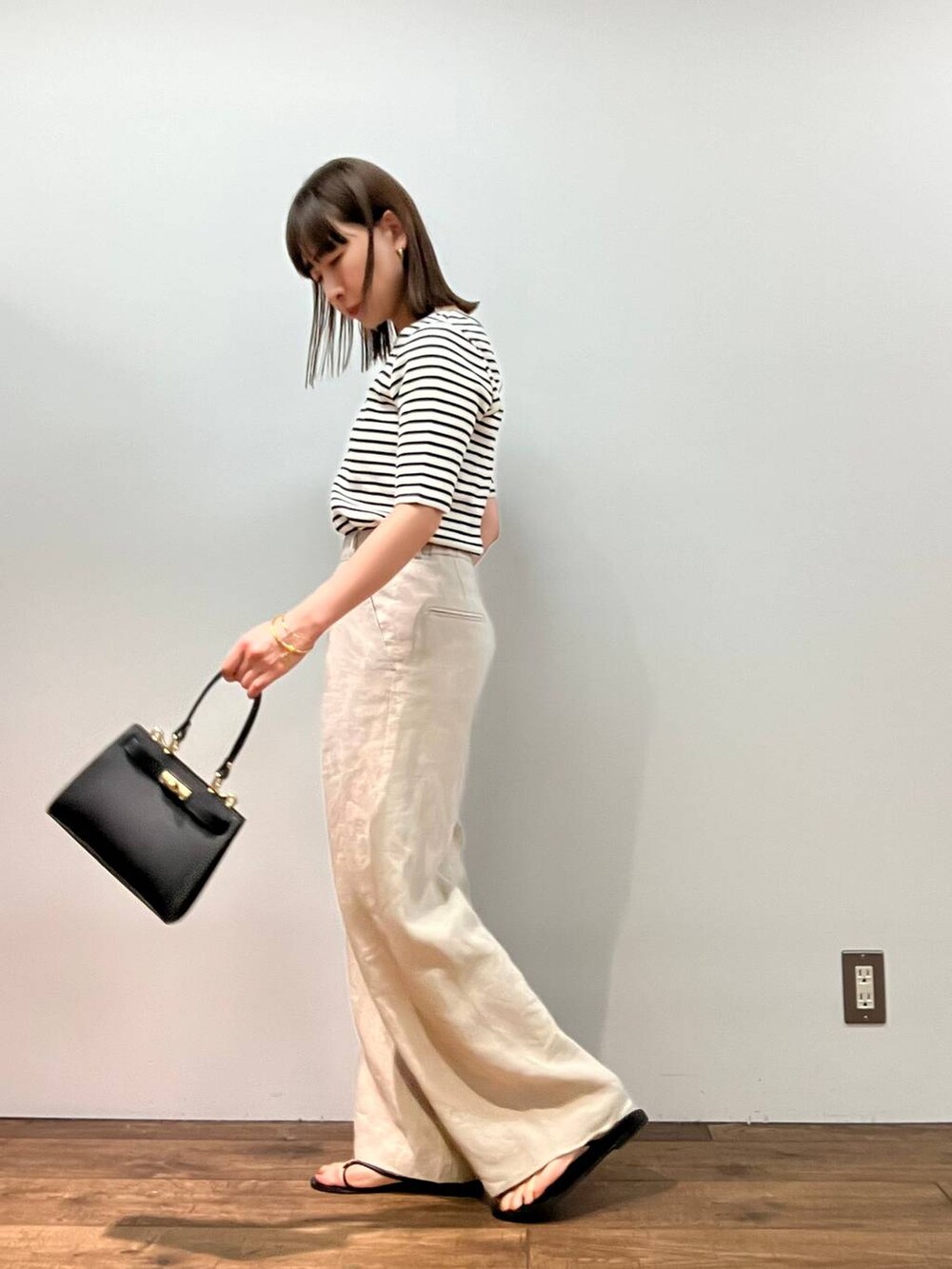 ホワイト系のTシャツ/カットソー、ベージュ系のその他パンツ、ブラック系のショルダーバッグを着用したレディースの春コーディネートの2枚目の写真