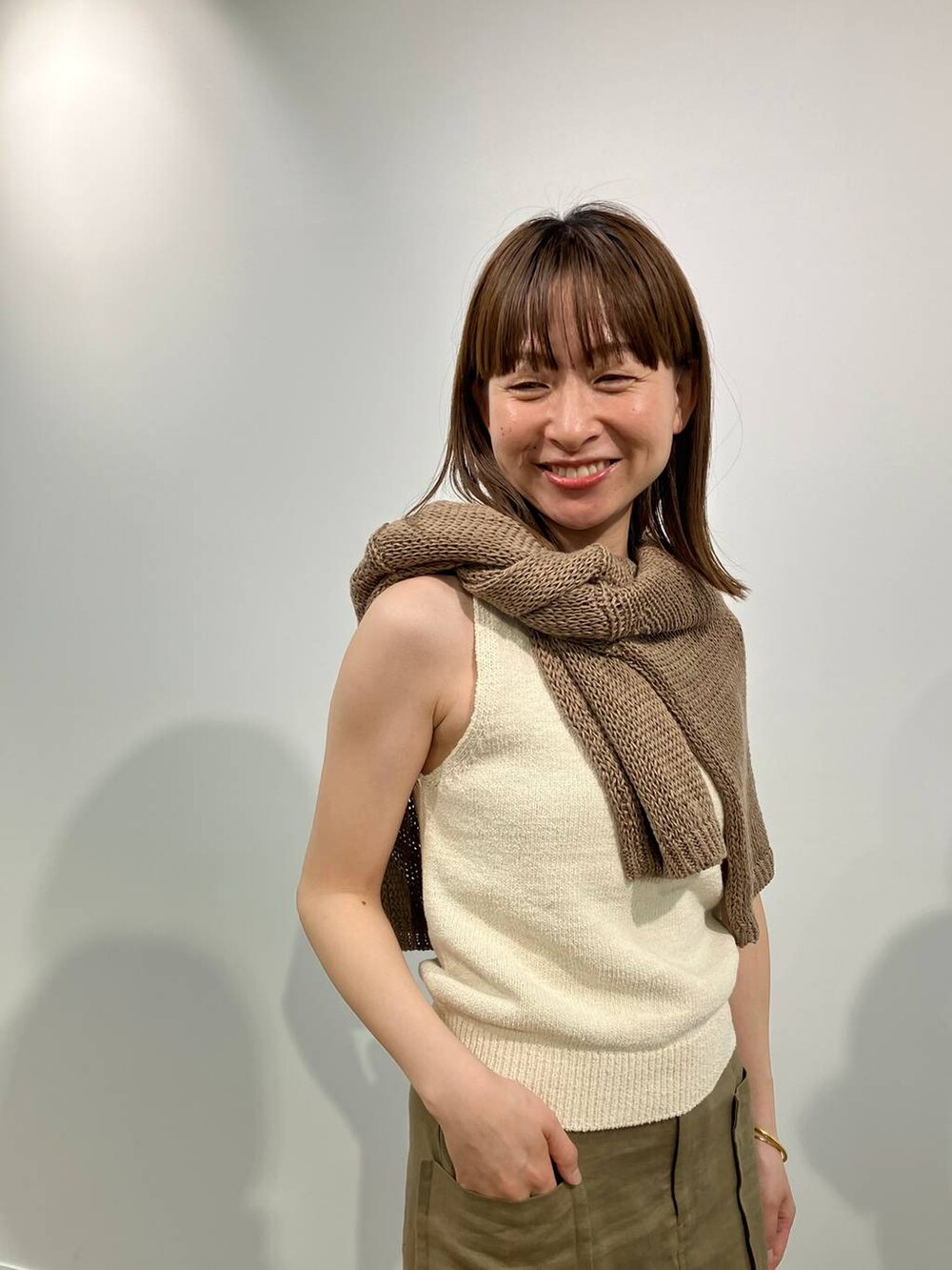 ベージュ系のニット/セーター、ベージュ系のタンクトップ、ブラック系のサンダルを着用したレディースの春コーディネートの3枚目の写真