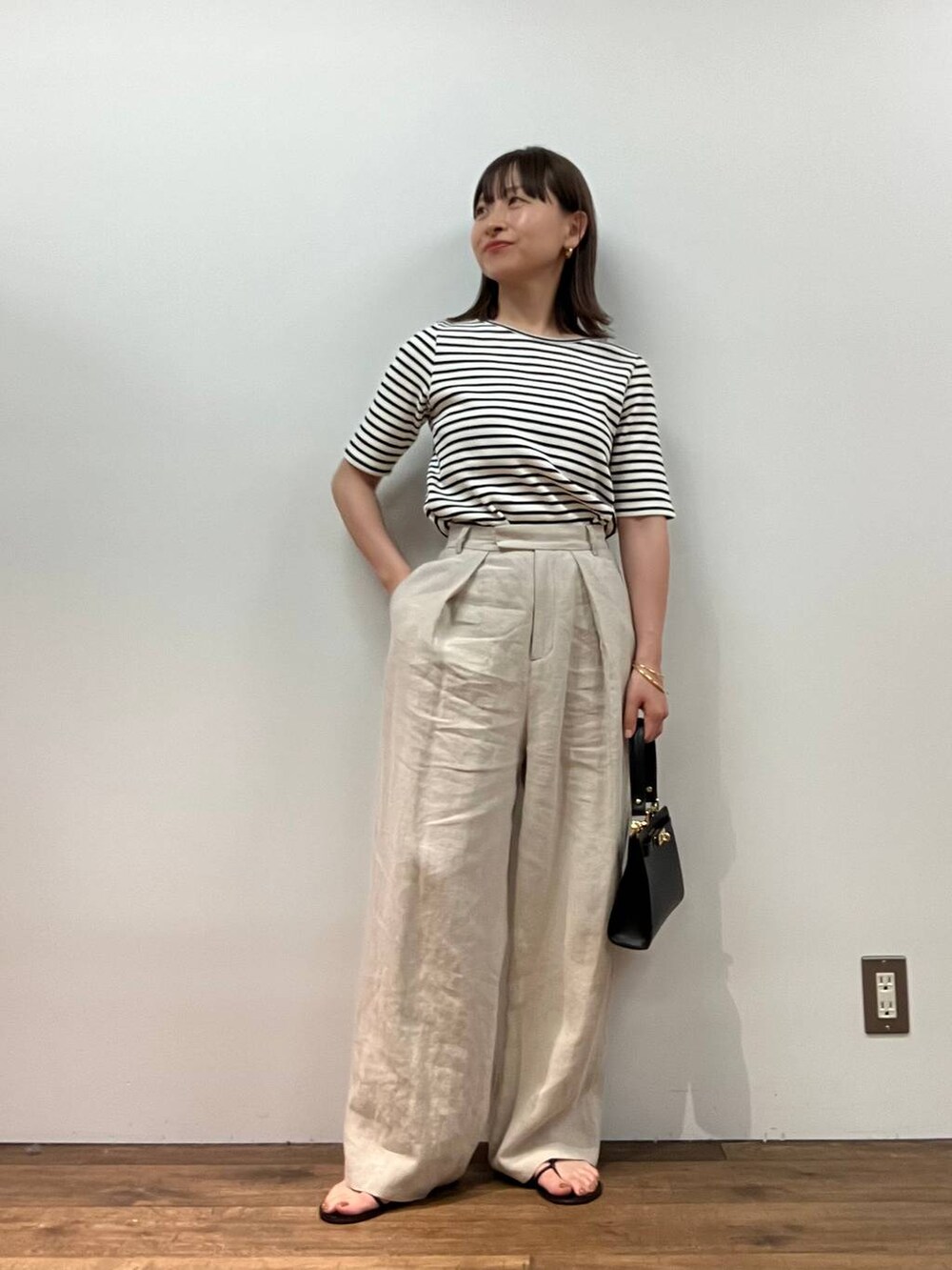 ホワイト系のTシャツ/カットソー、ベージュ系のその他パンツ、ブラック系のショルダーバッグを着用したレディースの春コーディネートの4枚目の写真