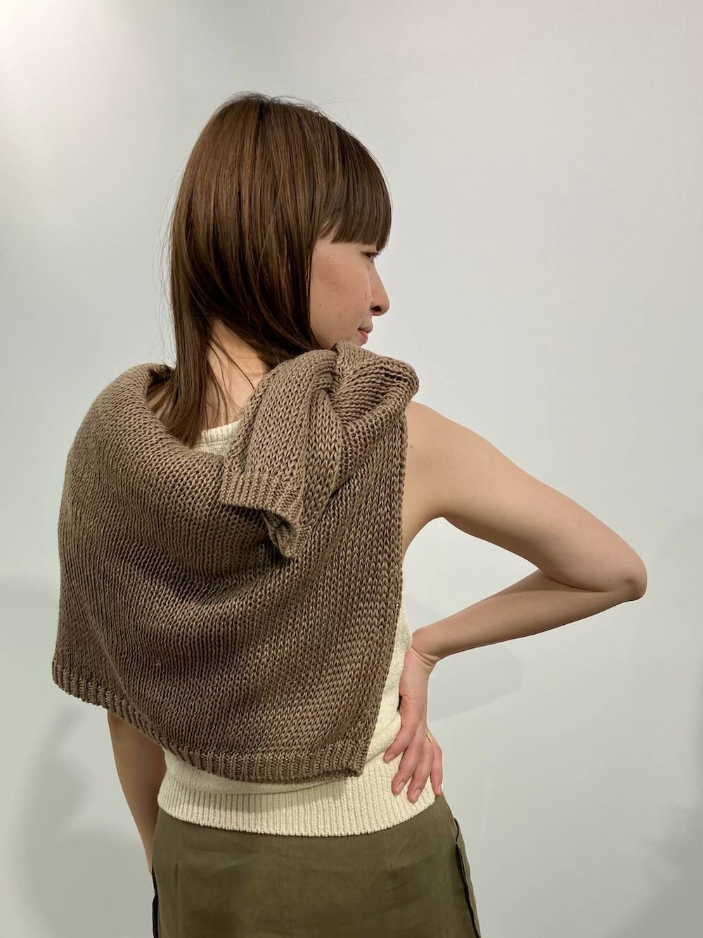 ベージュ系のニット/セーター、ベージュ系のタンクトップ、ブラック系のサンダルを着用したレディースの春コーディネートの4枚目の写真