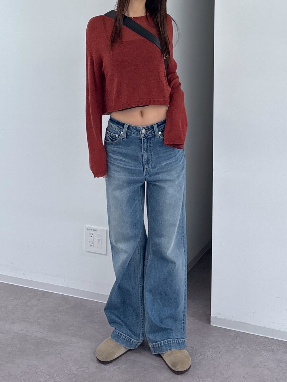 ブルー系のデニムパンツ、ブラック系のショルダーバッグ、レッド系のニット/セーターを着用したレディースの秋コーディネートの2枚目の写真