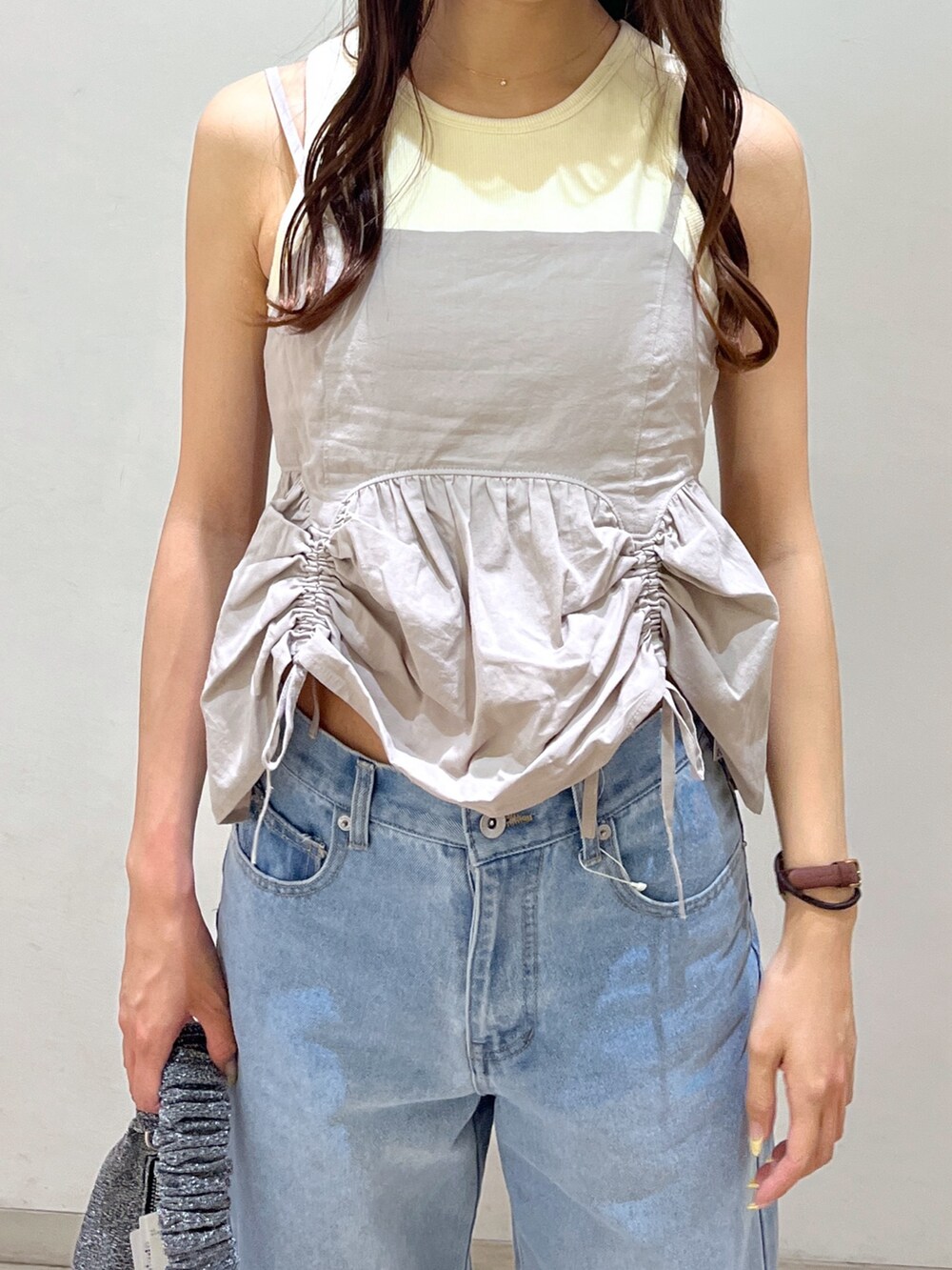 ブルー系のデニムパンツ、シルバー系のハンドバッグ、ホワイト系のタンクトップを着用したレディースの夏コーディネートの3枚目の写真