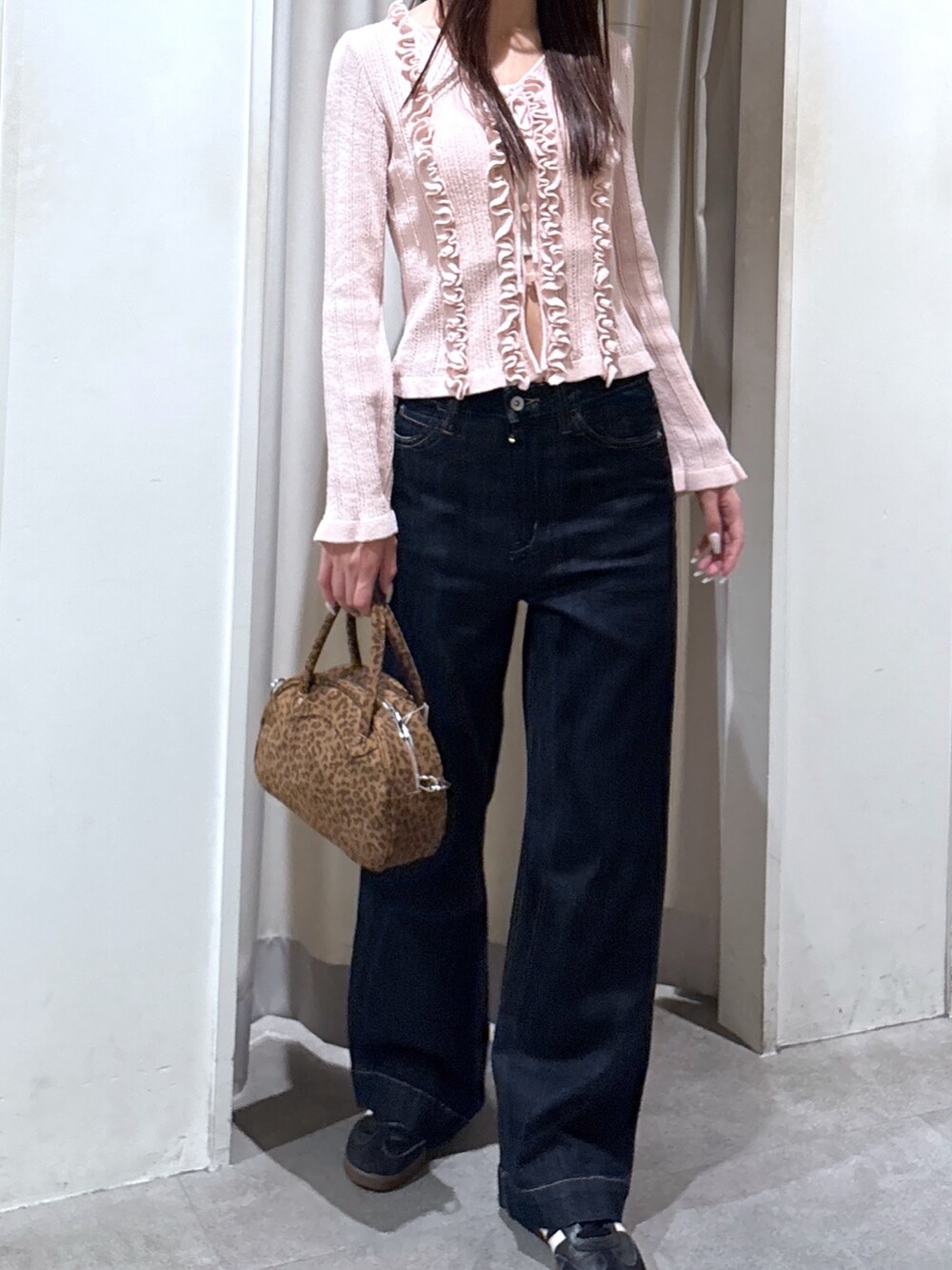 ブルー系のデニムパンツ、ピンク系のニット/セーター、ブラウン系のトートバッグを着用したレディースの春コーディネートの2枚目の写真