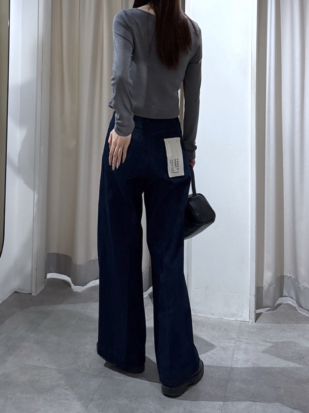 ブルー系のデニムパンツ、ブラック系のハンドバッグ、グレー系のTシャツ/カットソーを着用したレディースの冬コーディネートの2枚目の写真