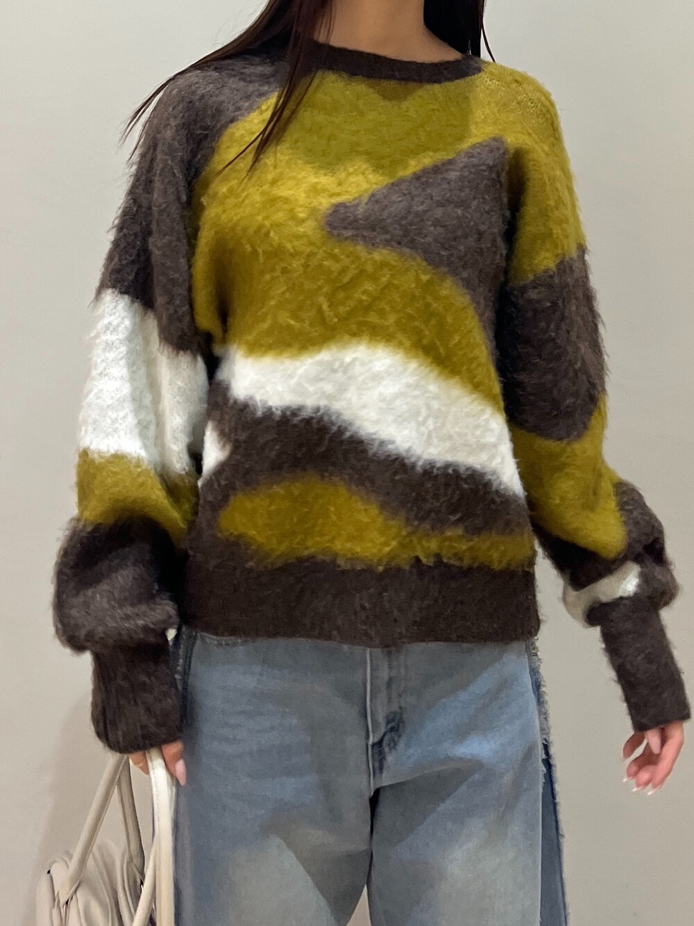 ブルー系のデニムパンツ、ホワイト系のショルダーバッグ、ブラウン系のニット/セーターを着用したレディースの冬コーディネートの4枚目の写真