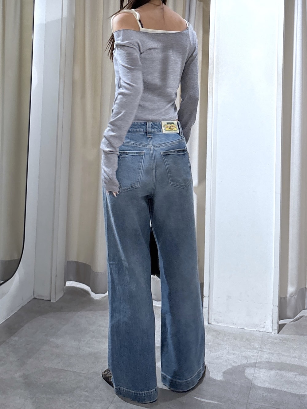 ブルー系のデニムパンツ、グレー系のTシャツ/カットソー、ブラック系のハンドバッグを着用したレディースの秋コーディネートの2枚目の写真