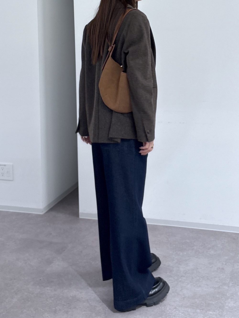 ブルー系のデニムパンツ、グレー系のTシャツ/カットソー、ブラウン系のハンドバッグを着用したレディースの秋コーディネートの2枚目の写真