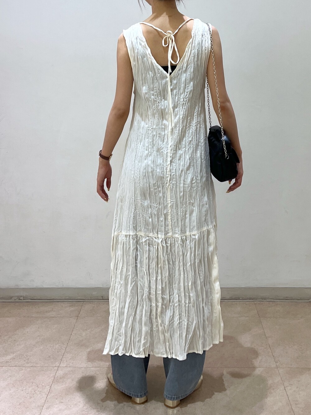 ブルー系のデニムパンツ、ゴールド系のサンダル、ホワイト系のワンピースを着用したレディースの夏コーディネートの2枚目の写真