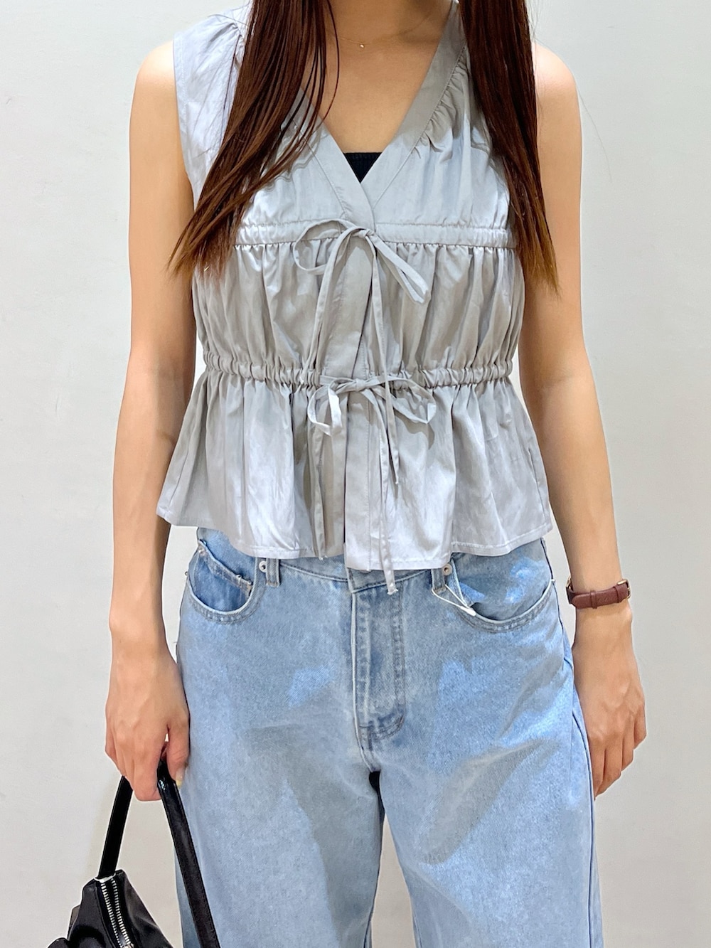 ブルー系のデニムパンツ、ブラック系のパンプス、ブラック系のハンドバッグを着用したレディースの夏コーディネートの2枚目の写真