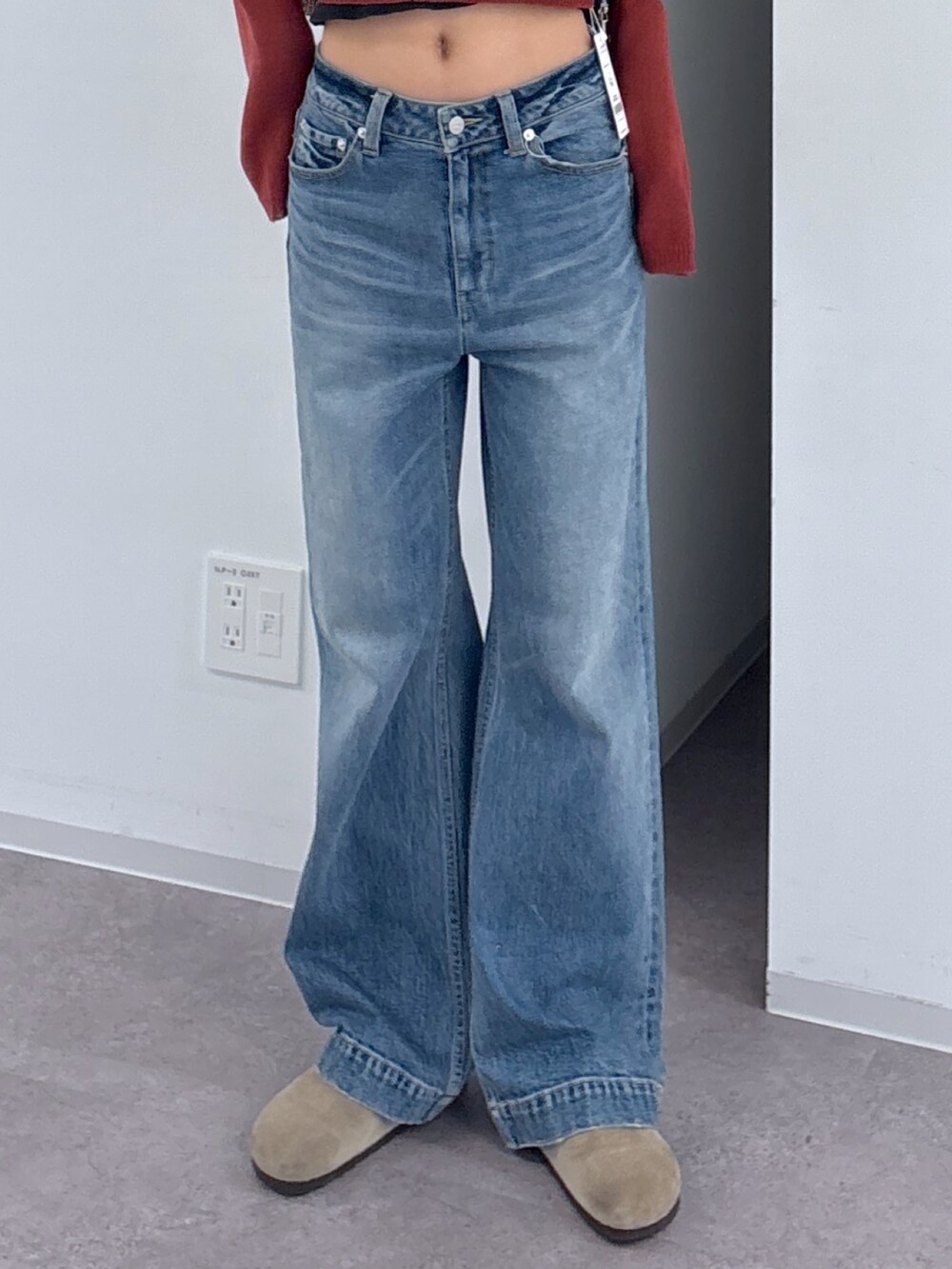 ブルー系のデニムパンツ、ブラック系のショルダーバッグ、レッド系のニット/セーターを着用したレディースの秋コーディネートの3枚目の写真