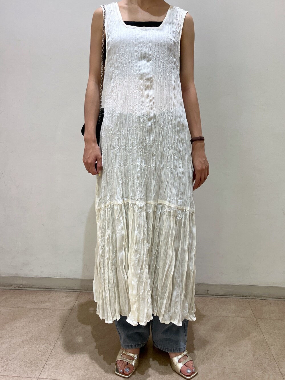 ブルー系のデニムパンツ、ゴールド系のサンダル、ホワイト系のワンピースを着用したレディースの夏コーディネートの3枚目の写真