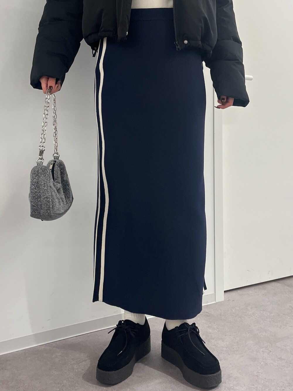 シルバー系のハンドバッグ、ブルー系のスカート、ホワイト系のニット/セーターを着用したレディースの冬コーディネートの4枚目の写真