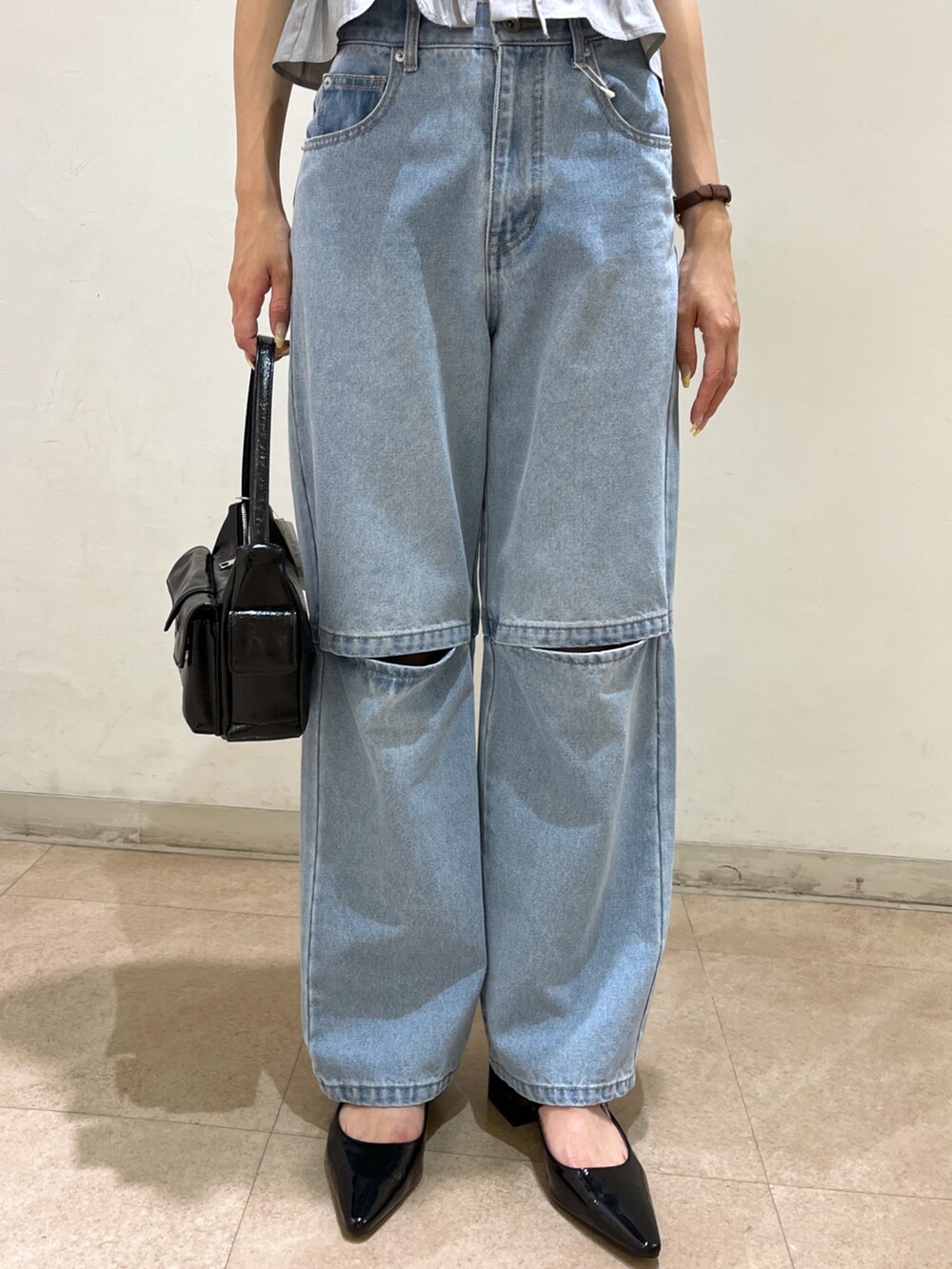 ブルー系のデニムパンツ、ブラック系のパンプス、ブラック系のハンドバッグを着用したレディースの夏コーディネートの3枚目の写真