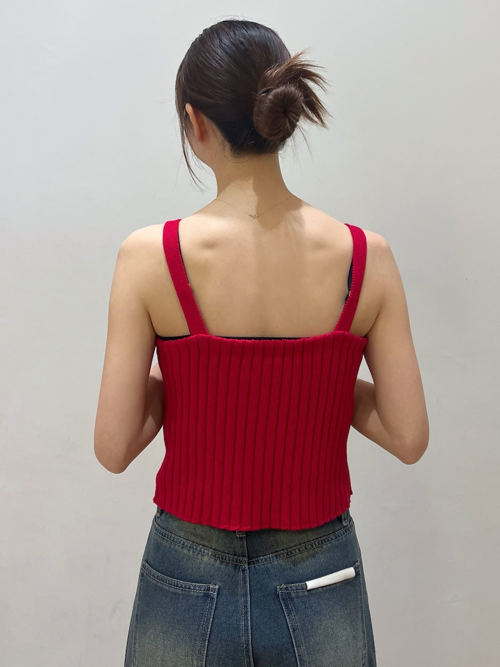 レッド系のタンクトップ、ブラック系のショルダーバッグ、ブルー系のデニムパンツを着用したレディースの夏コーディネートの3枚目の写真