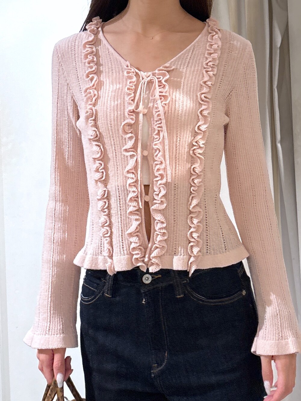 ブルー系のデニムパンツ、ピンク系のニット/セーター、ブラウン系のトートバッグを着用したレディースの春コーディネートの3枚目の写真