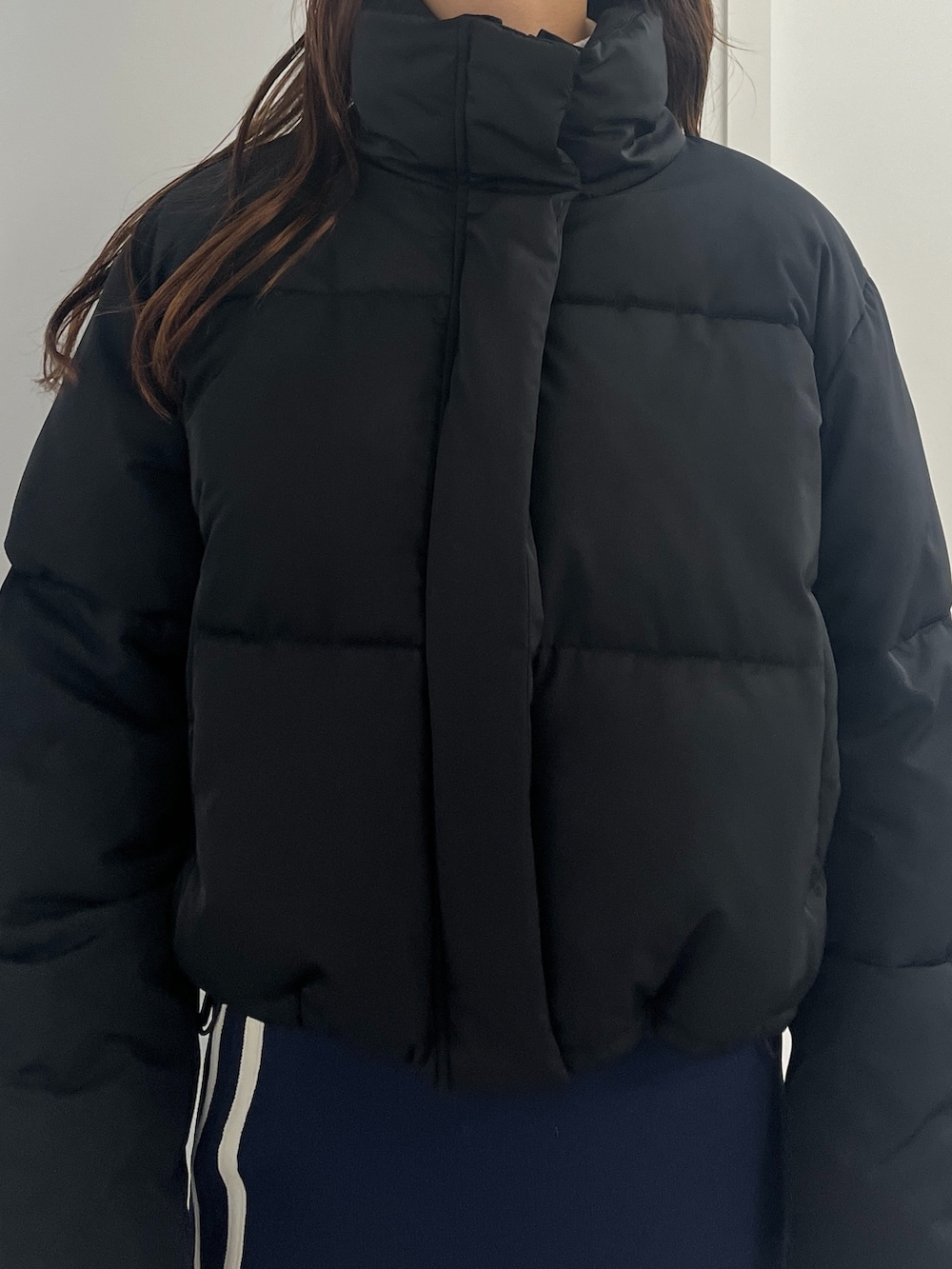 シルバー系のハンドバッグ、ブルー系のスカート、ホワイト系のニット/セーターを着用したレディースの冬コーディネートの3枚目の写真