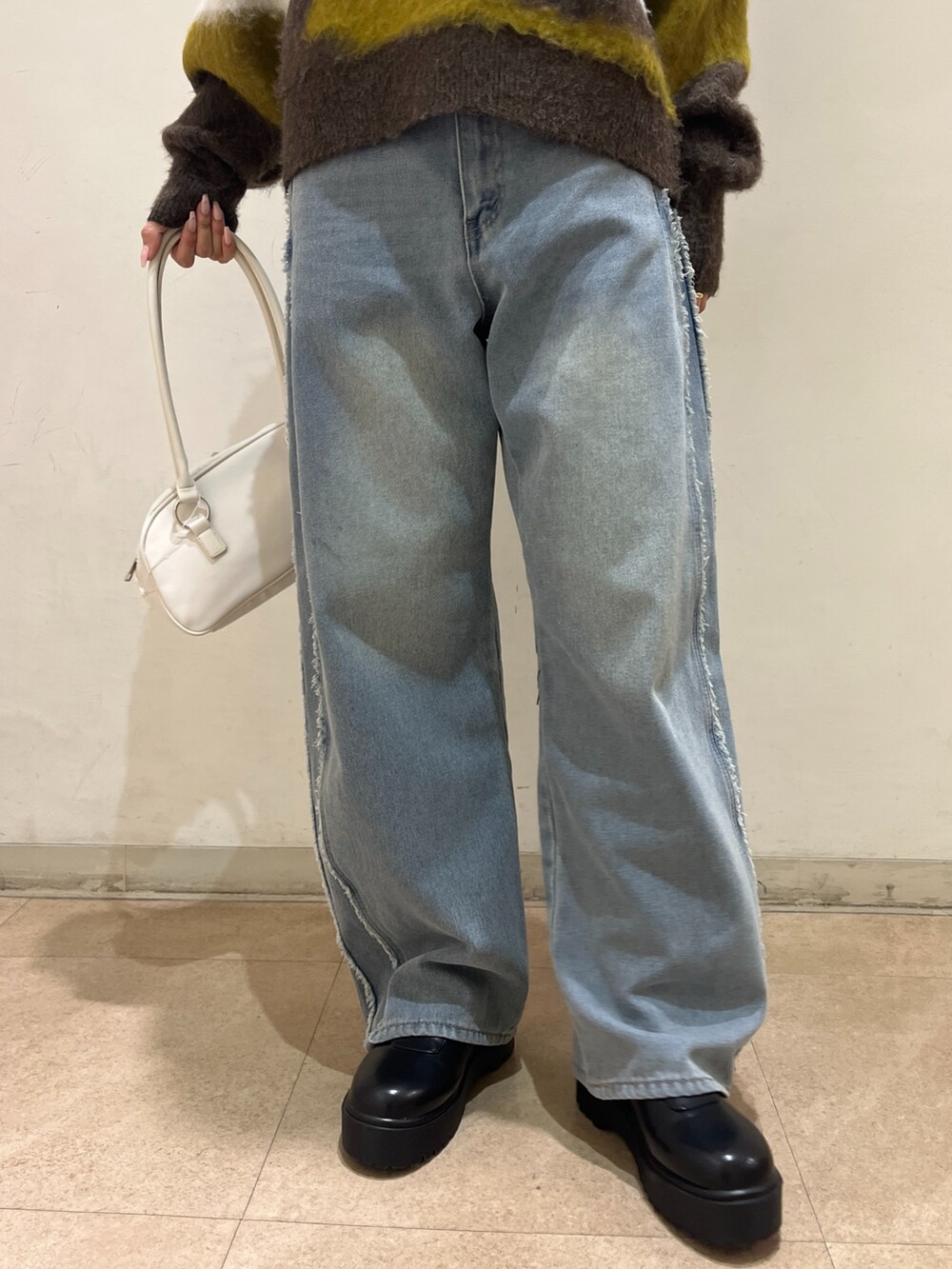 ブルー系のデニムパンツ、ホワイト系のショルダーバッグ、ブラウン系のニット/セーターを着用したレディースの冬コーディネートの5枚目の写真