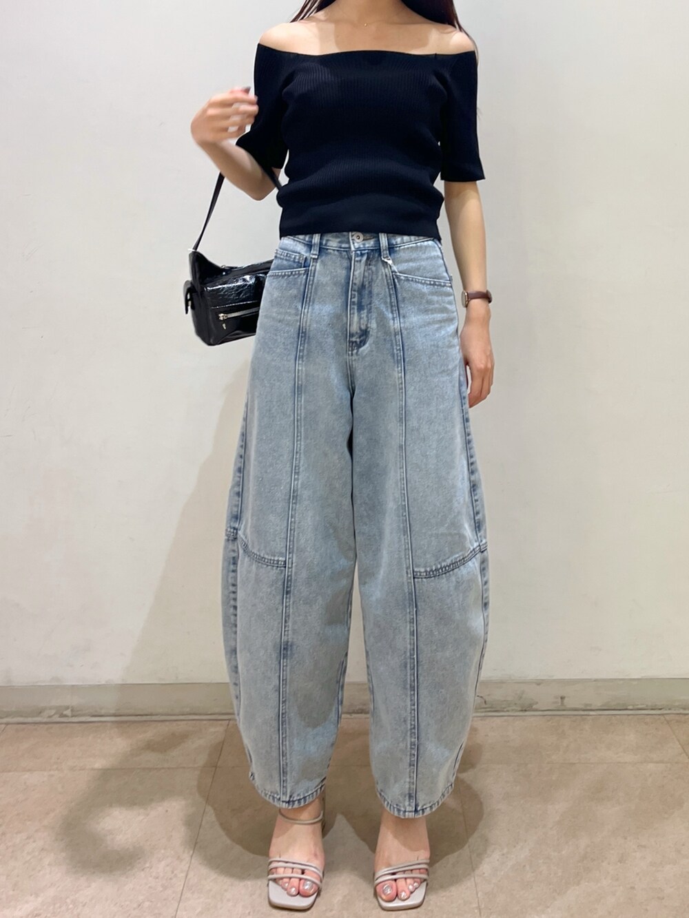 ブラック系のニット/セーター、ブラック系のハンドバッグ、ブルー系のデニムパンツを着用したレディースの夏コーディネートの3枚目の写真