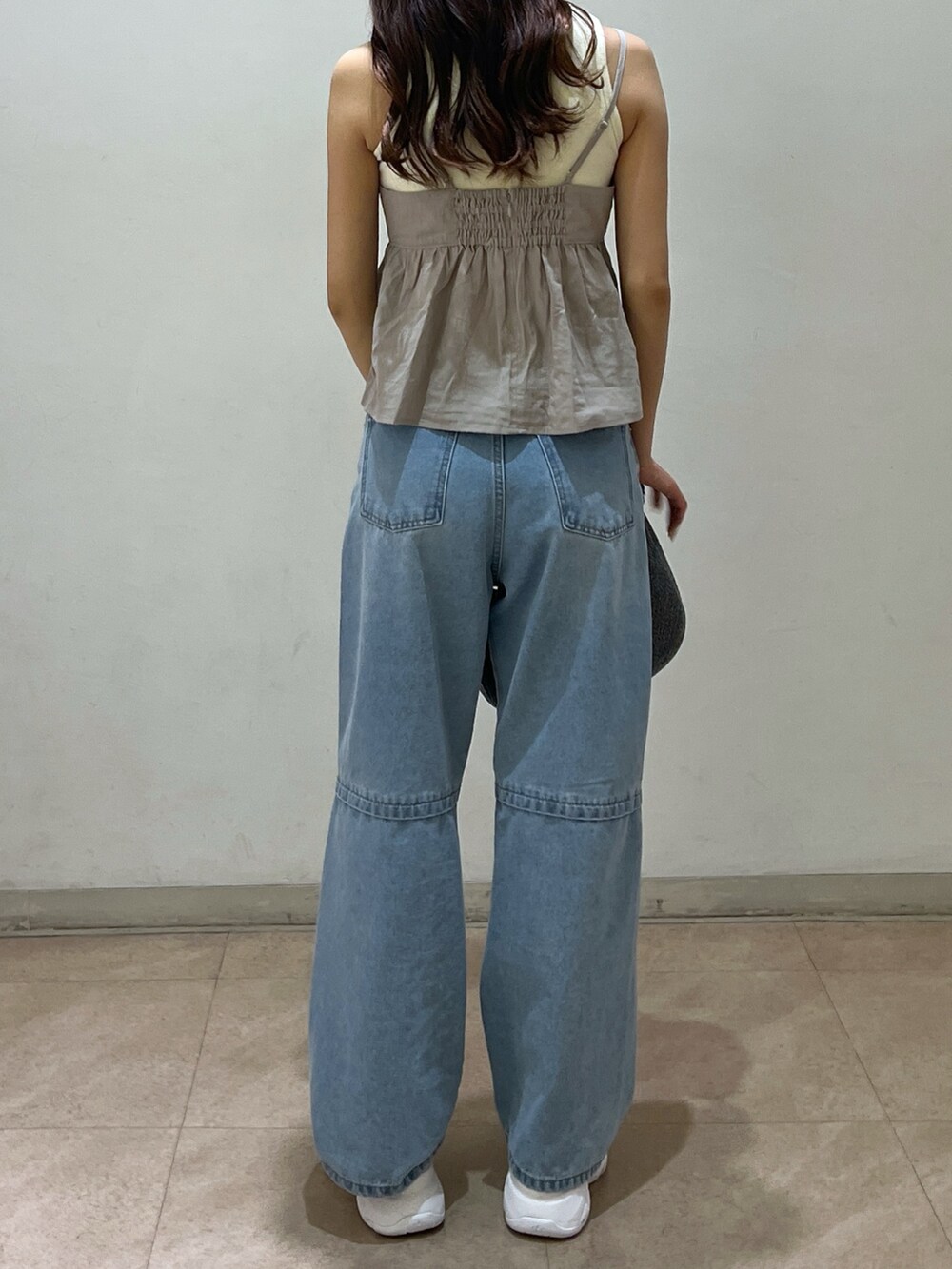 ブルー系のデニムパンツ、シルバー系のハンドバッグ、ホワイト系のタンクトップを着用したレディースの夏コーディネートの2枚目の写真