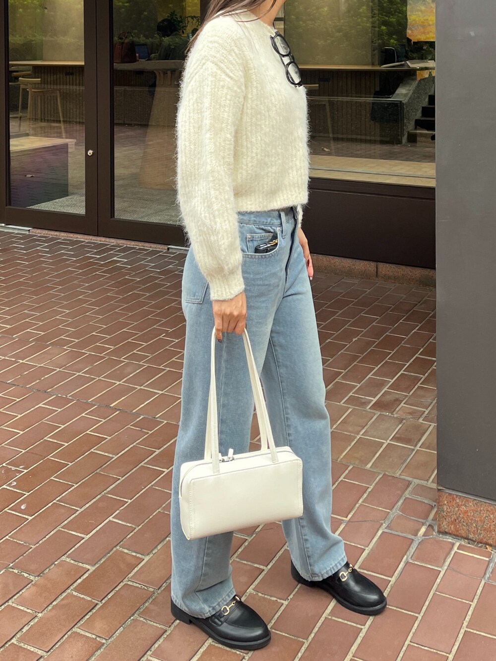 ブルー系のデニムパンツ、ホワイト系のショルダーバッグ、ホワイト系のニット/セーターを着用したレディースの冬コーディネートの3枚目の写真