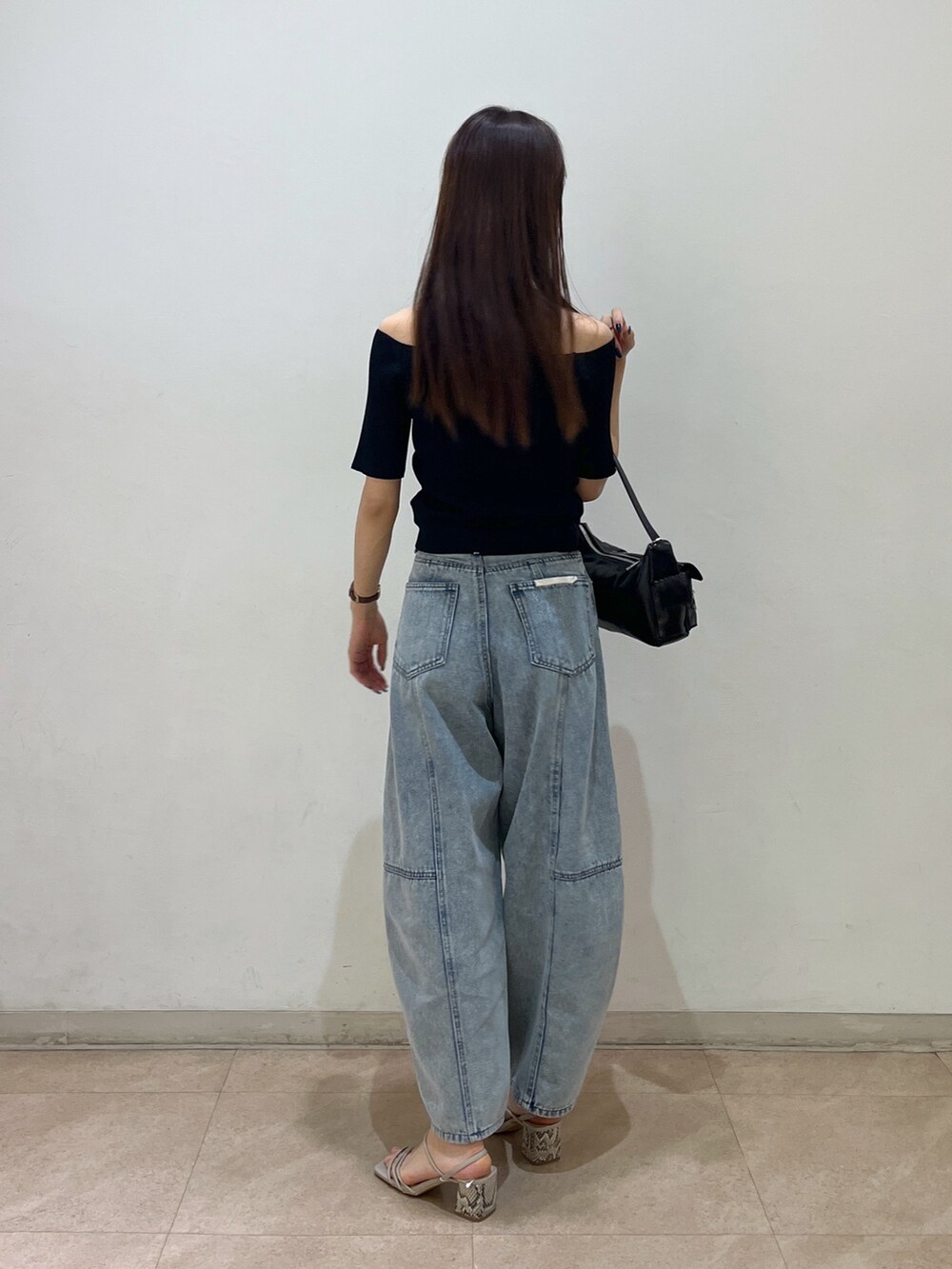 ブラック系のニット/セーター、ブラック系のハンドバッグ、ブルー系のデニムパンツを着用したレディースの夏コーディネートの2枚目の写真