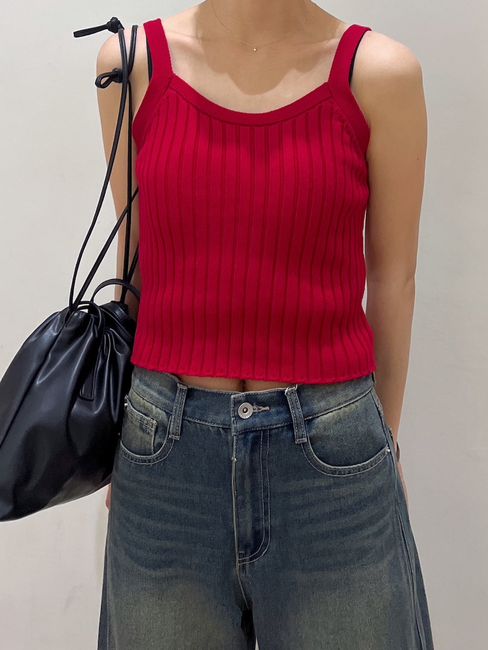 レッド系のタンクトップ、ブラック系のショルダーバッグ、ブルー系のデニムパンツを着用したレディースの夏コーディネートの2枚目の写真