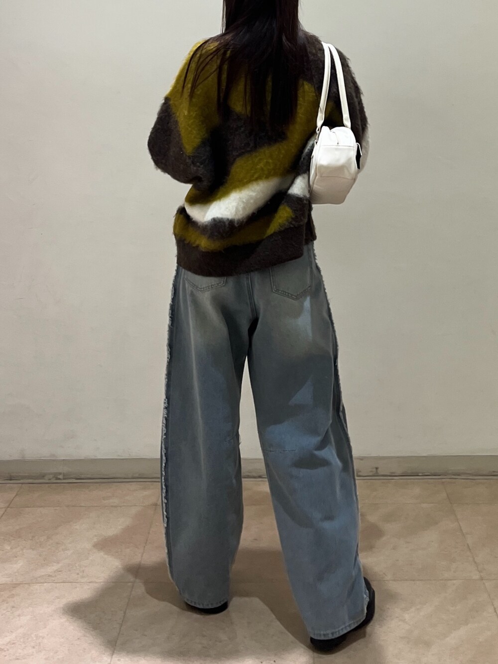 ブルー系のデニムパンツ、ホワイト系のショルダーバッグ、ブラウン系のニット/セーターを着用したレディースの冬コーディネートの3枚目の写真