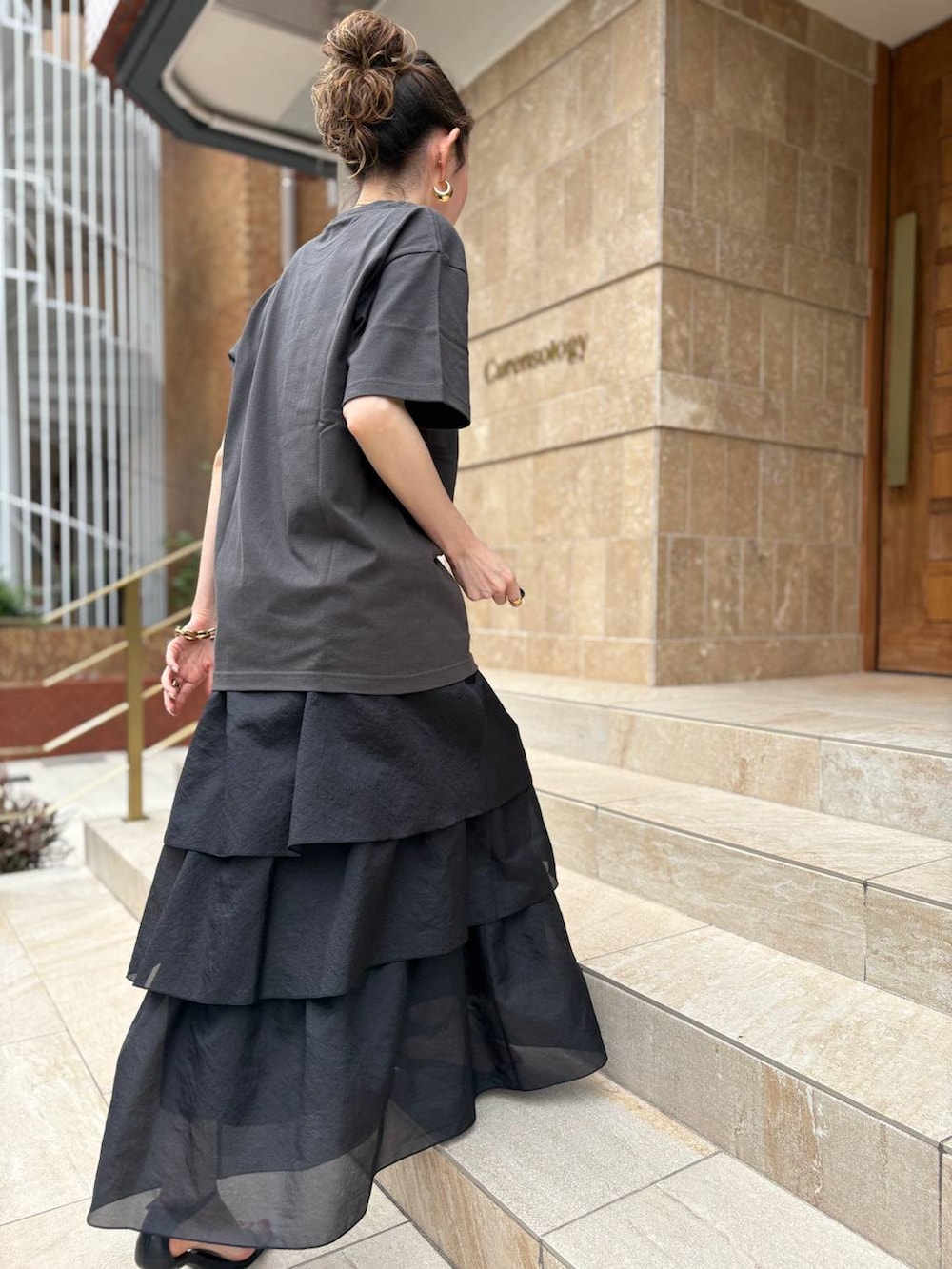 ブラック系のスカート、ブラック系のTシャツ/カットソー、ゴールド系のピアス（両耳用）を着用したレディースの夏コーディネートの2枚目の写真