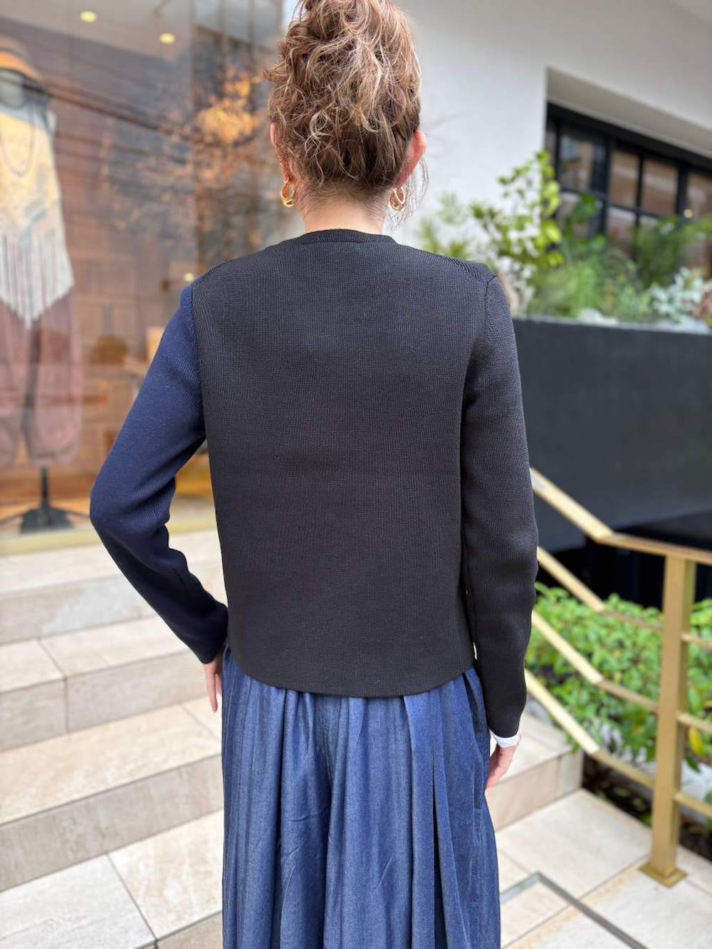 ブルー系のデニムパンツ、ゴールド系のピアス(両耳用)を着用したレディースの秋コーディネートの5枚目の写真