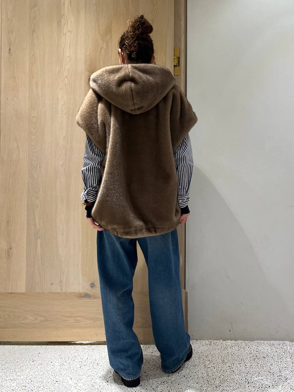 ブルー系のデニムパンツ、ブラック系のニット/セーター、ブルー系のシャツ/ブラウスを着用したレディースの秋コーディネートの4枚目の写真