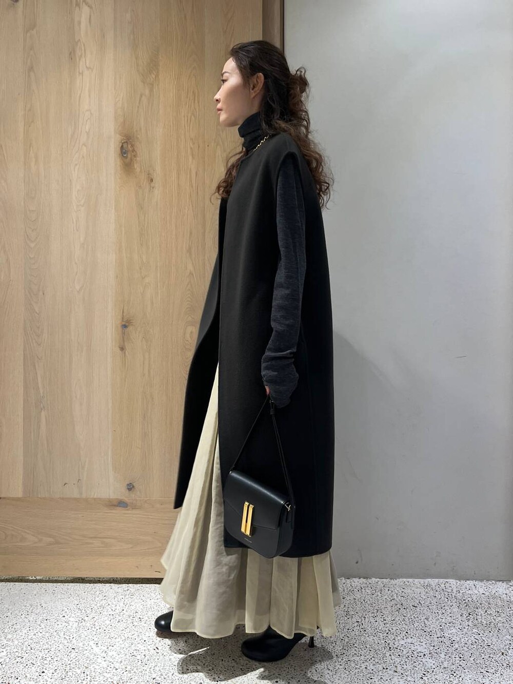 グレー系のベスト、グレー系のニット/セーター、ホワイト系のスカートを着用したレディースの秋コーディネートの3枚目の写真