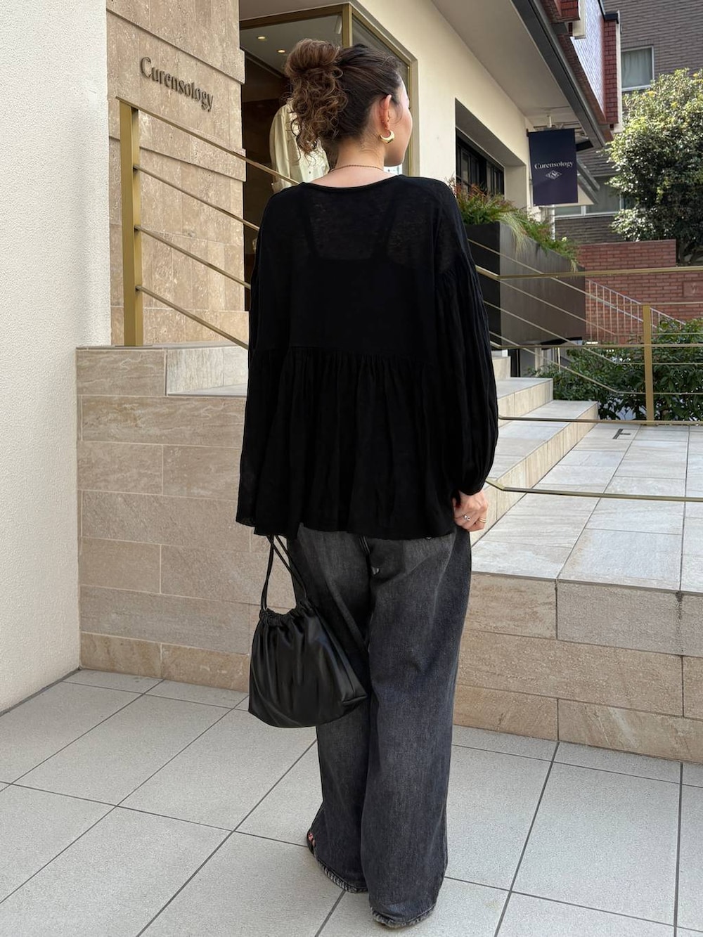 ブラック系のデニムパンツ、ブラック系のクラッチバッグ、ブラック系のニット/セーターを着用したレディースの秋コーディネートの3枚目の写真