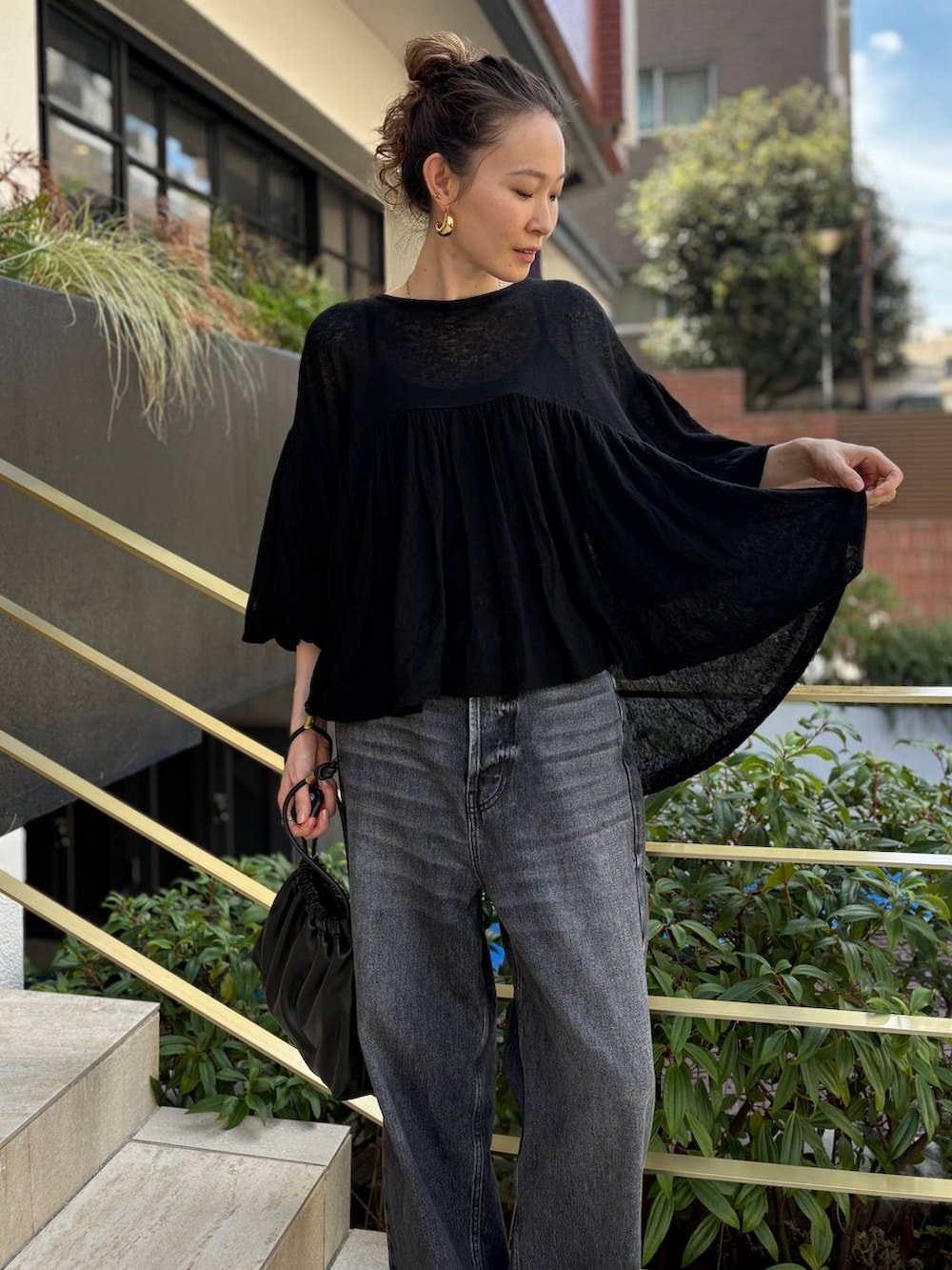 ブラック系のデニムパンツ、ブラック系のクラッチバッグ、ブラック系のニット/セーターを着用したレディースの秋コーディネートの4枚目の写真