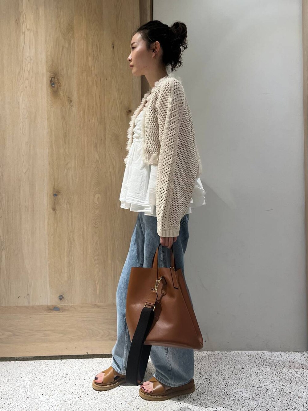 ベージュ系のカーディガン/ボレロ、ホワイト系のキャミソール、ブルー系のデニムパンツを着用したレディースの春コーディネートの2枚目の写真