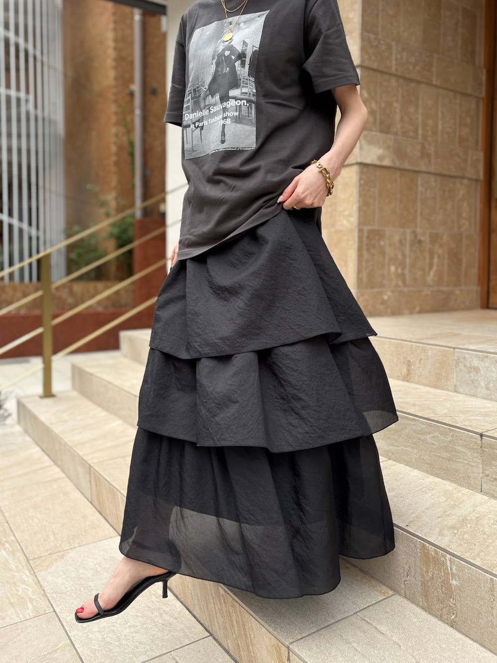 ブラック系のスカート、ブラック系のTシャツ/カットソー、ゴールド系のピアス（両耳用）を着用したレディースの夏コーディネートの3枚目の写真