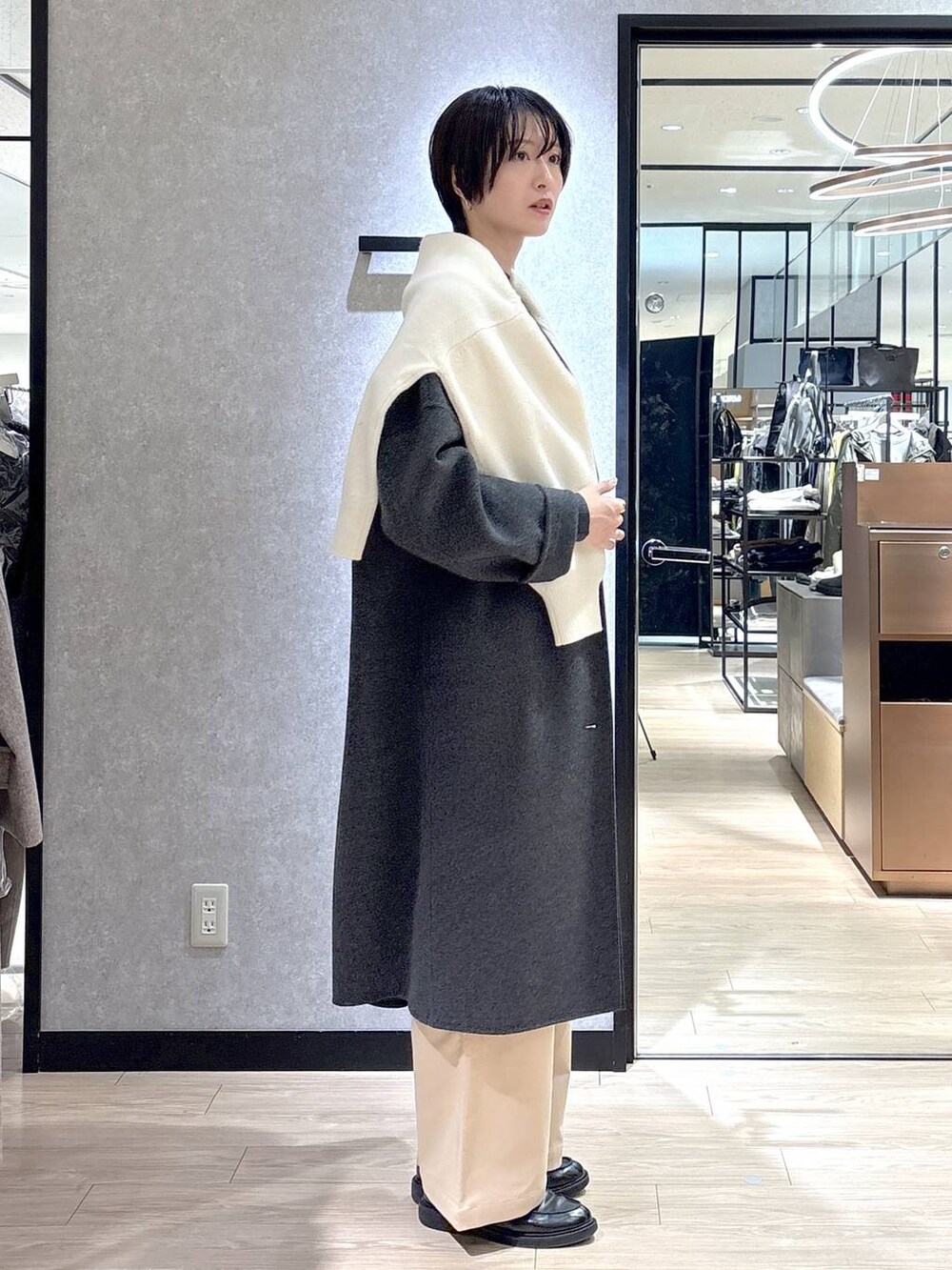 ブラック系のショルダーバッグ、ホワイト系のニット/セーター、グレー系のチェスターコートを着用したレディースの秋コーディネートの2枚目の写真