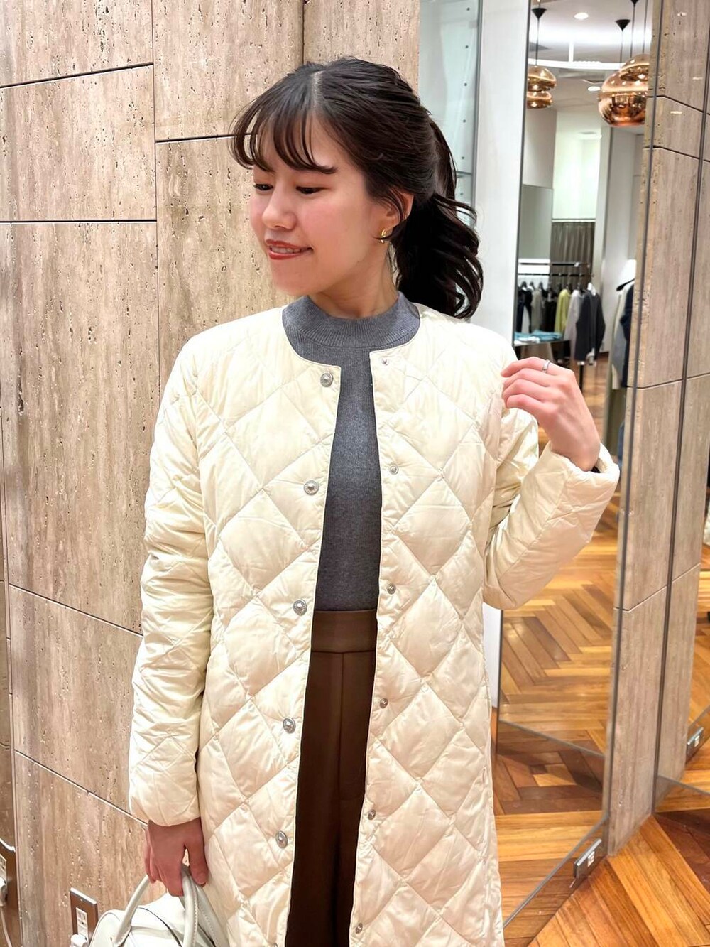 グレー系のニット/セーター、ブラウン系のその他パンツ、ホワイト系のダウンジャケット/コートを着用したレディースの秋コーディネートの4枚目の写真