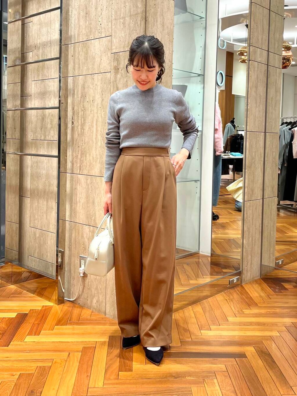 グレー系のニット/セーター、ブラウン系のその他パンツ、ホワイト系のダウンジャケット/コートを着用したレディースの秋コーディネートの6枚目の写真