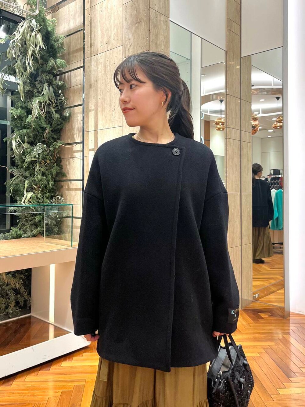 イエロー系のワンピース、ブラック系のその他アウター、ブラック系のハンドバッグを着用したレディースの冬コーディネートの4枚目の写真