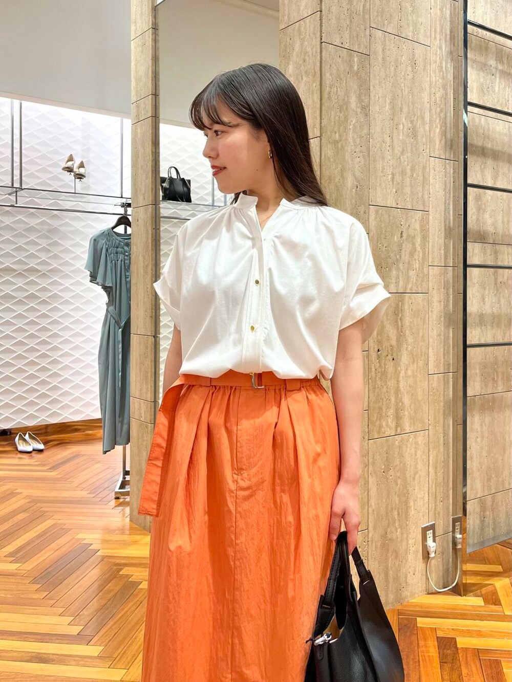 ホワイト系のシャツ/ブラウス、オレンジ系のスカートを着用したレディースの夏コーディネートの4枚目の写真