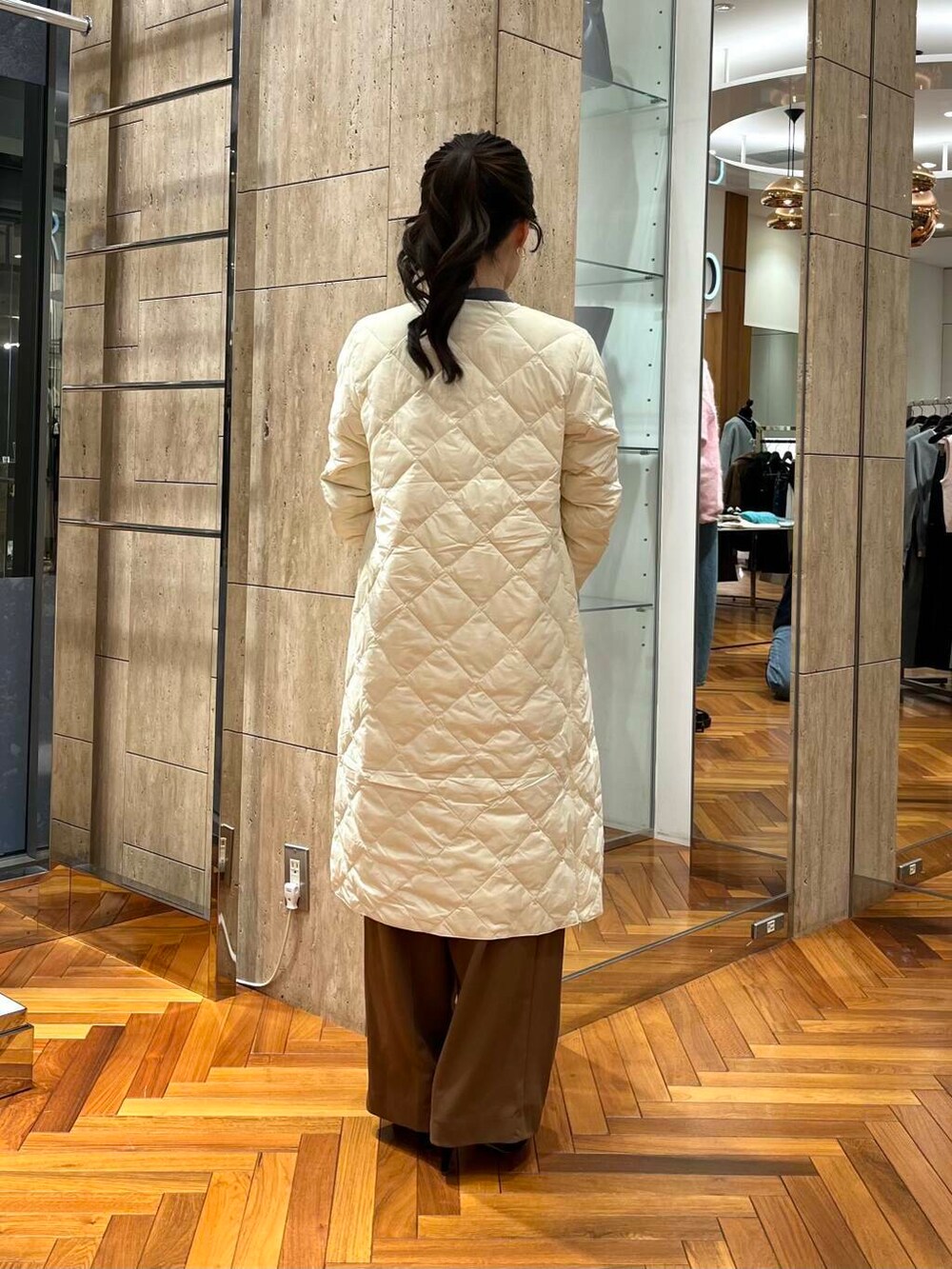 グレー系のニット/セーター、ブラウン系のその他パンツ、ホワイト系のダウンジャケット/コートを着用したレディースの秋コーディネートの3枚目の写真