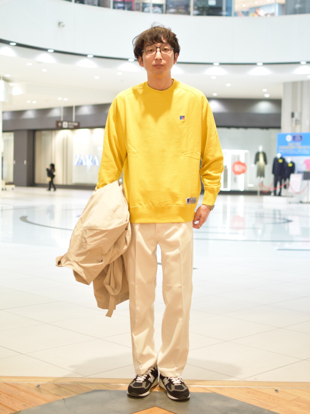 イエロー系のスウェット、ベージュ系のステンカラーコート、ホワイト系のその他パンツを着用したメンズの冬コーディネートの2枚目の写真