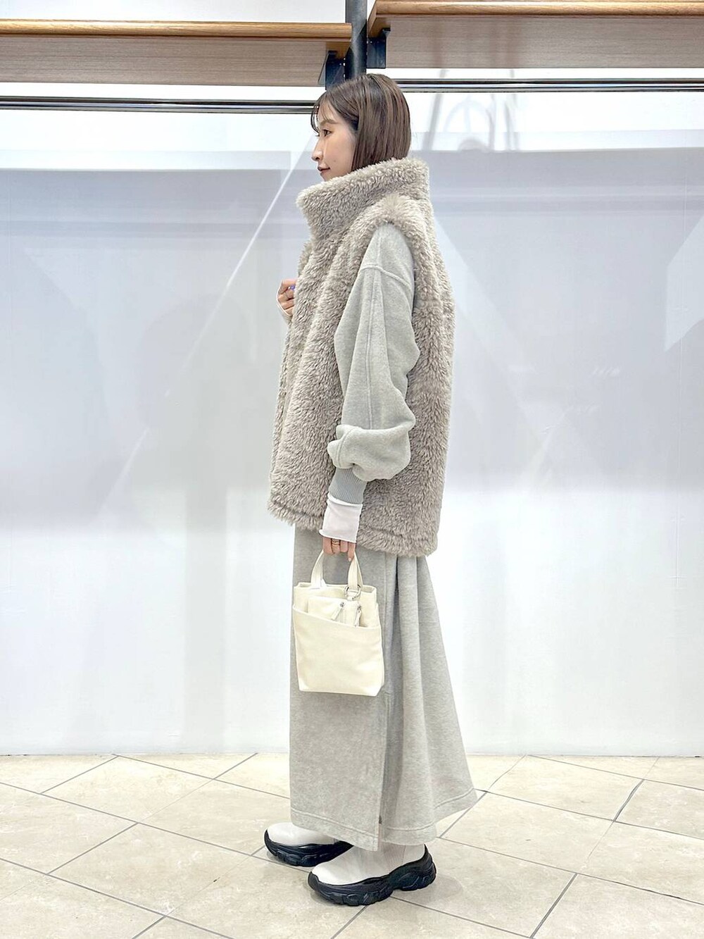 ホワイト系のブルゾン、ホワイト系のショルダーバッグ、グレー系のワンピースを着用したレディースの秋コーディネートの2枚目の写真