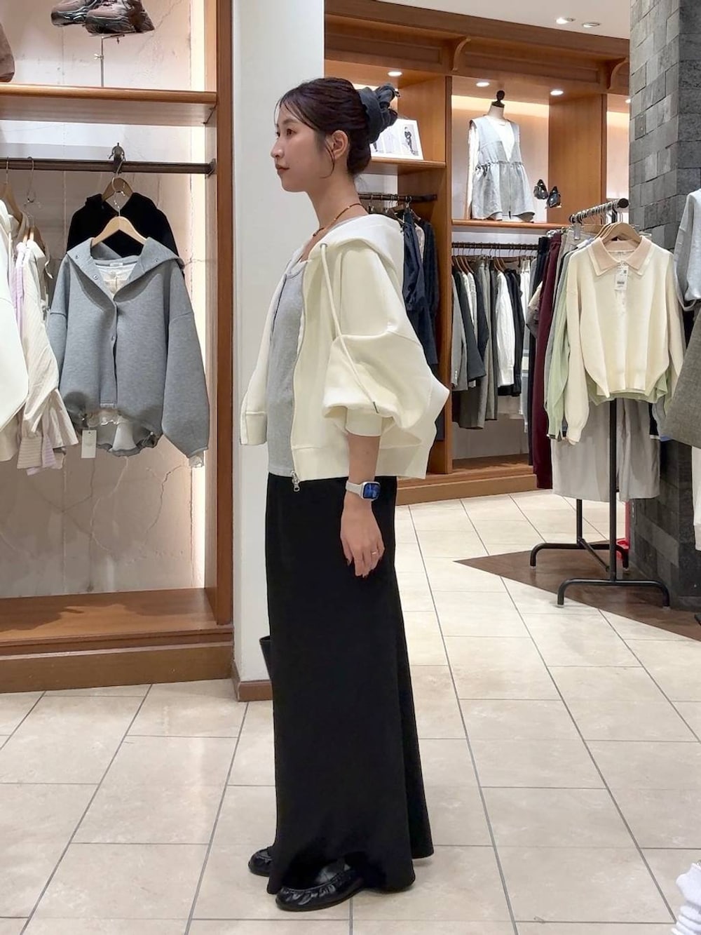 ブラック系のスカート、ベージュ系のパーカー、ブラック系のトートバッグを着用したレディースの春コーディネートの2枚目の写真