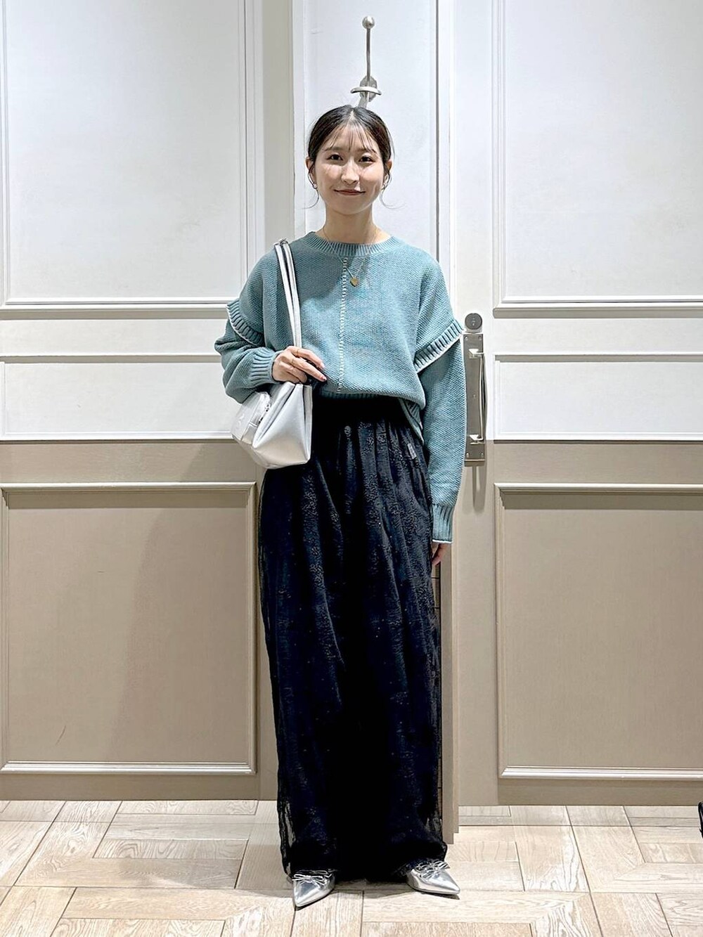 グリーン系のニット/セーター、シルバー系のパンプス、ブラック系のデニムパンツを着用したレディースの秋コーディネートの6枚目の写真