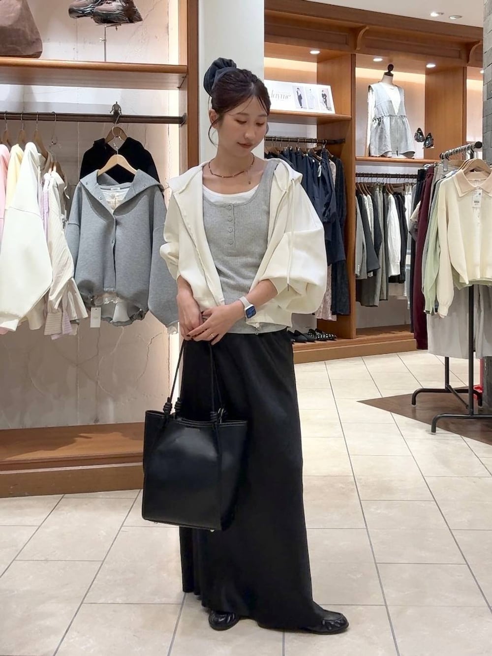 ブラック系のスカート、ベージュ系のパーカー、ブラック系のトートバッグを着用したレディースの春コーディネートの4枚目の写真