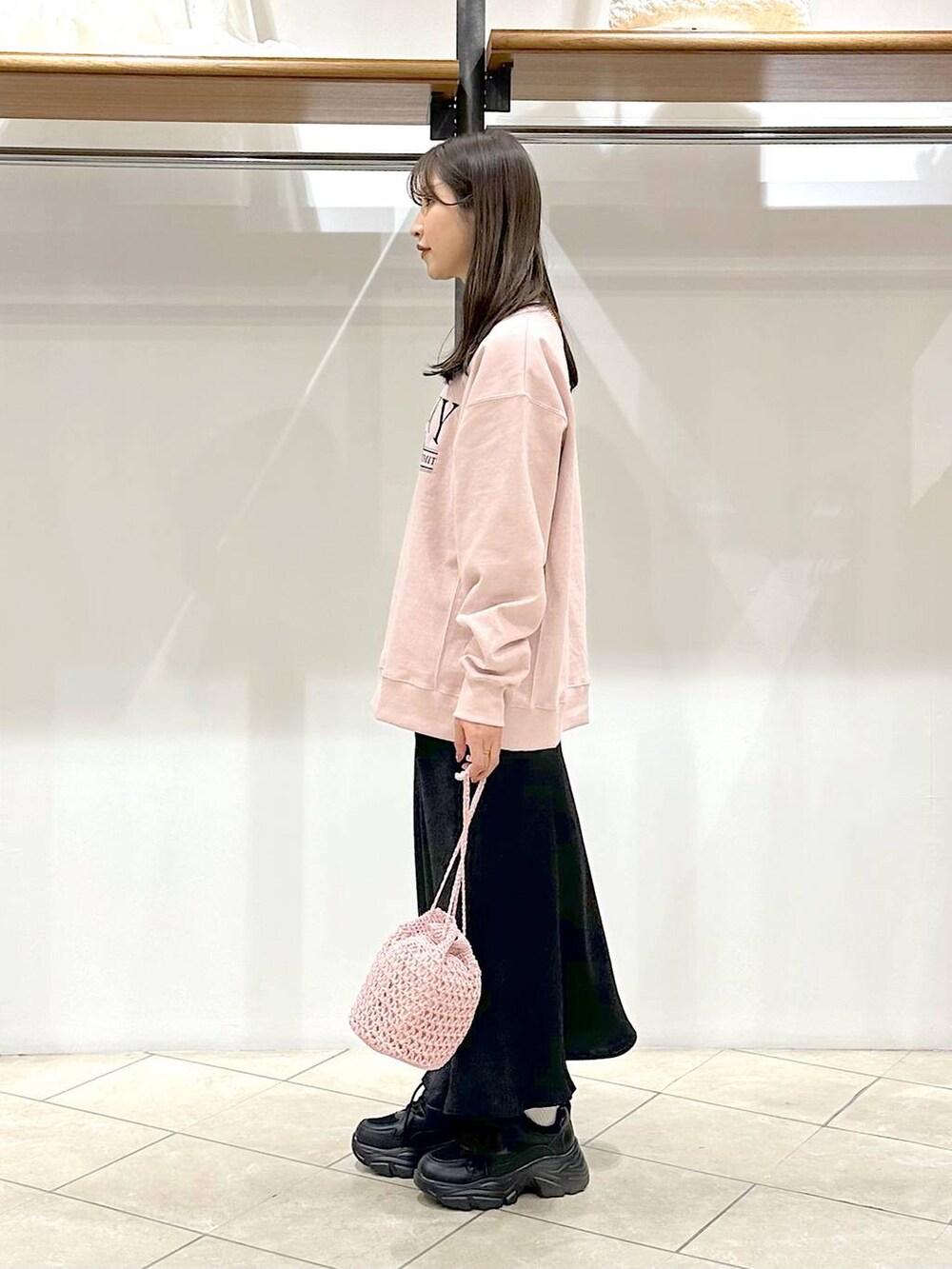 ブラック系のスカート、ブラック系のスニーカー、ピンク系のスウェットを着用したレディースの春コーディネートの2枚目の写真