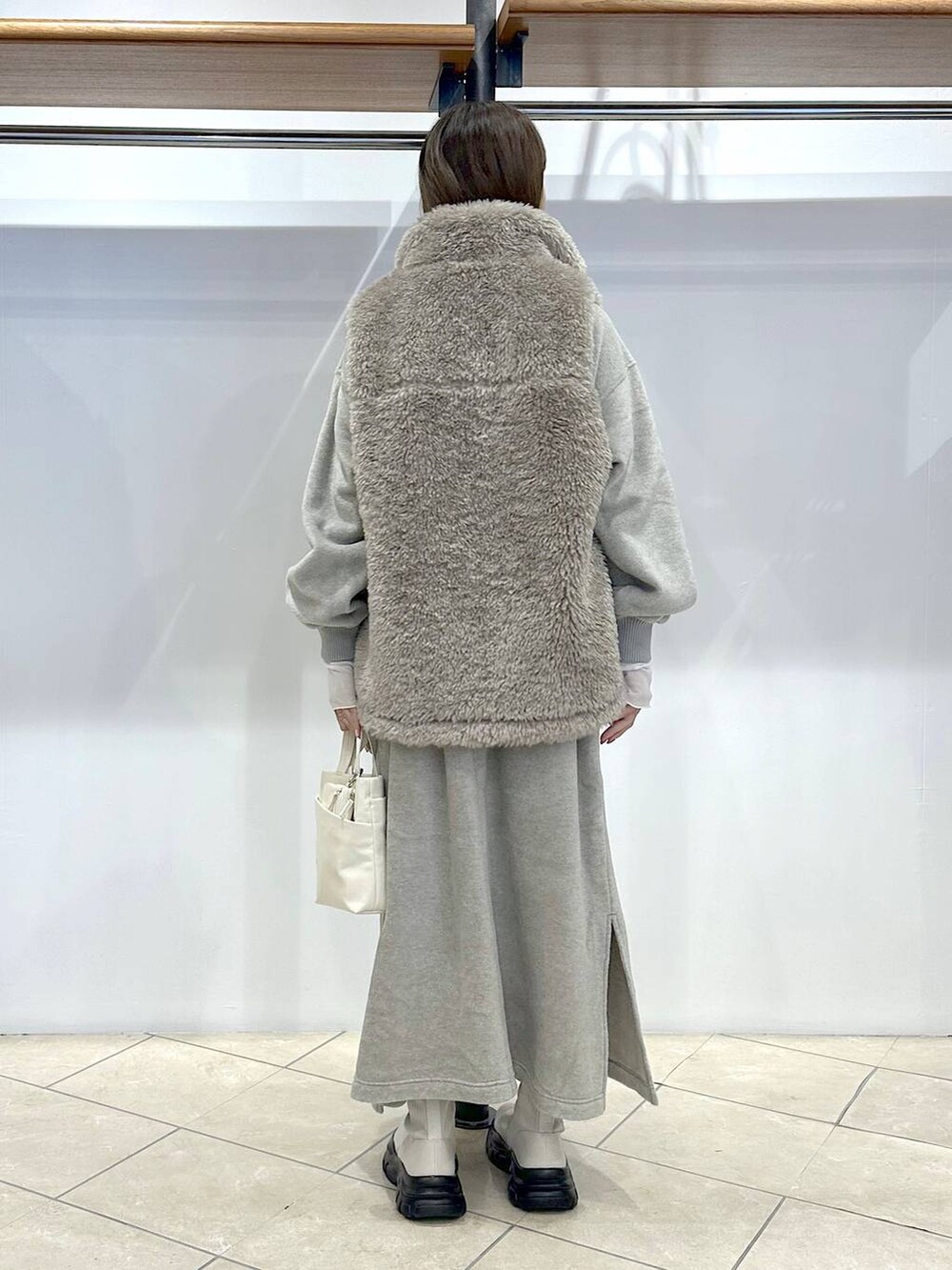 ホワイト系のブルゾン、ホワイト系のショルダーバッグ、グレー系のワンピースを着用したレディースの秋コーディネートの3枚目の写真