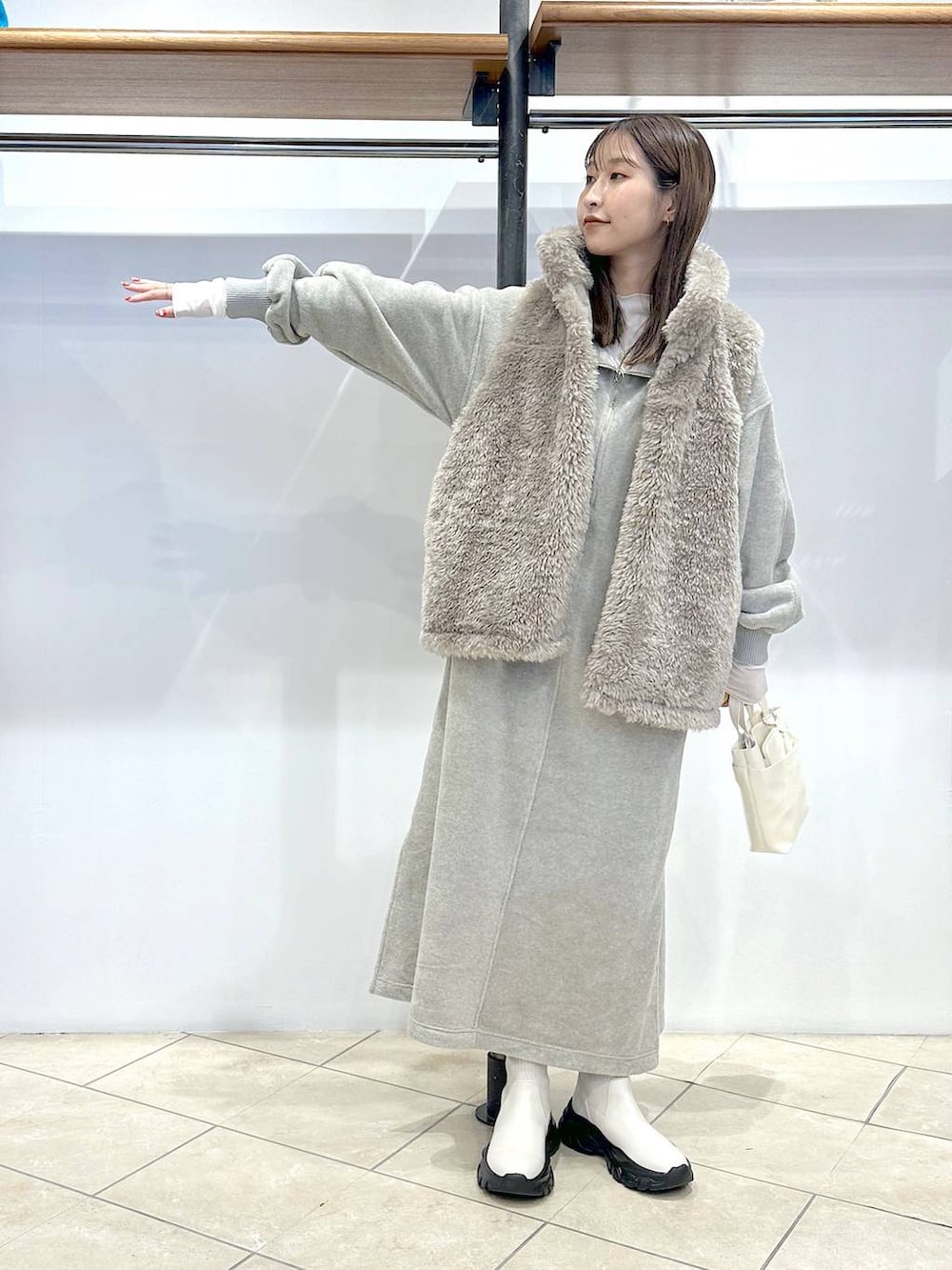 ホワイト系のブルゾン、ホワイト系のショルダーバッグ、グレー系のワンピースを着用したレディースの秋コーディネートの4枚目の写真