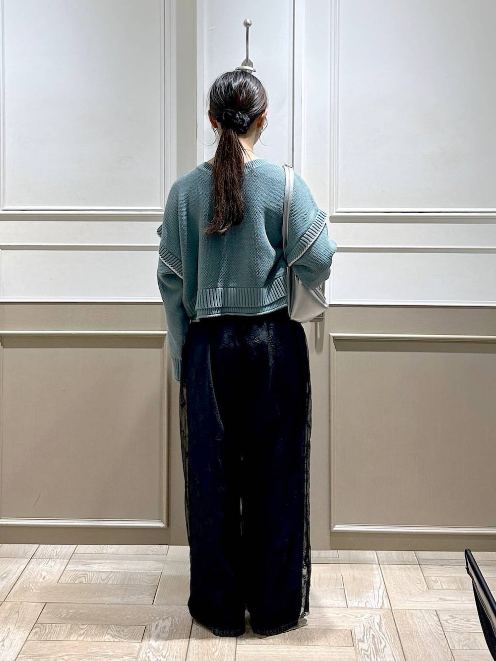 グリーン系のニット/セーター、シルバー系のパンプス、ブラック系のデニムパンツを着用したレディースの秋コーディネートの4枚目の写真